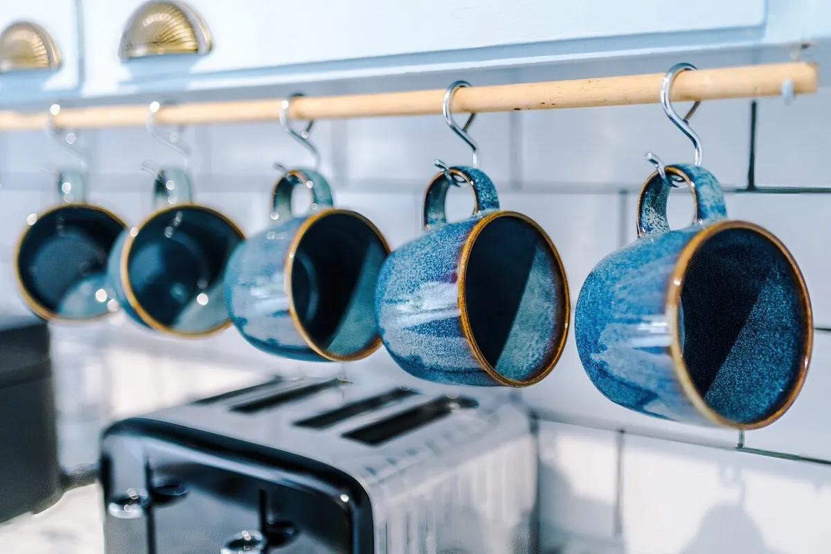 Blue mugs on a rail above the toaster