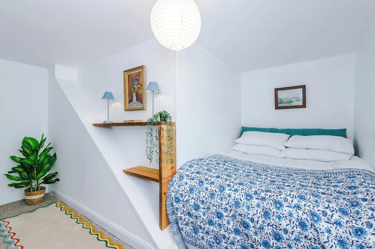 Double bed with a blue floral quilt under a sloping ceiling