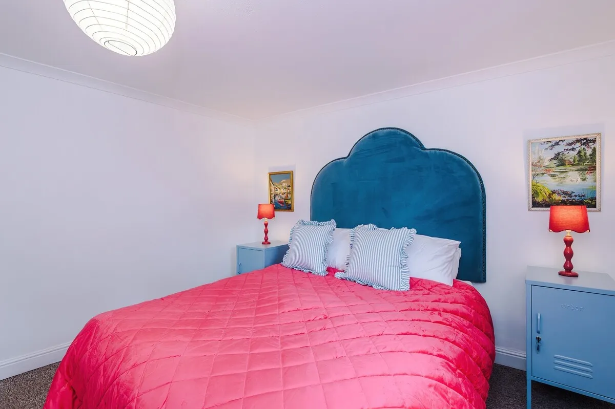 Double bedroom with a teal headboard and pink quilt