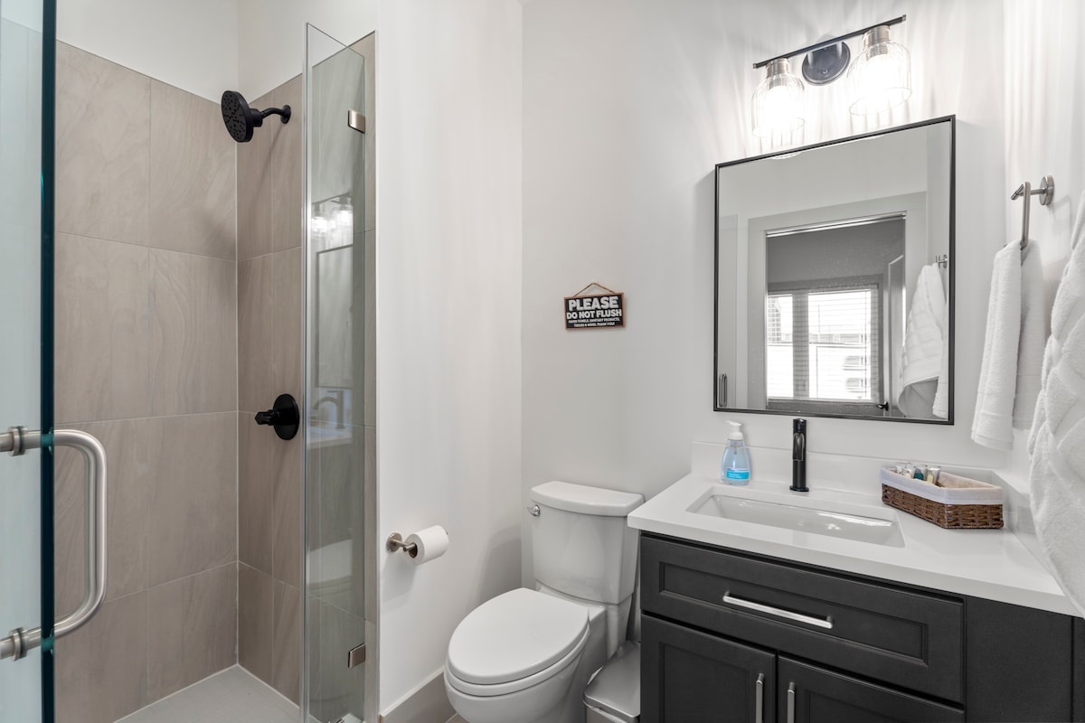 A modern bathroom with a shower, toilet, sink, and mirror