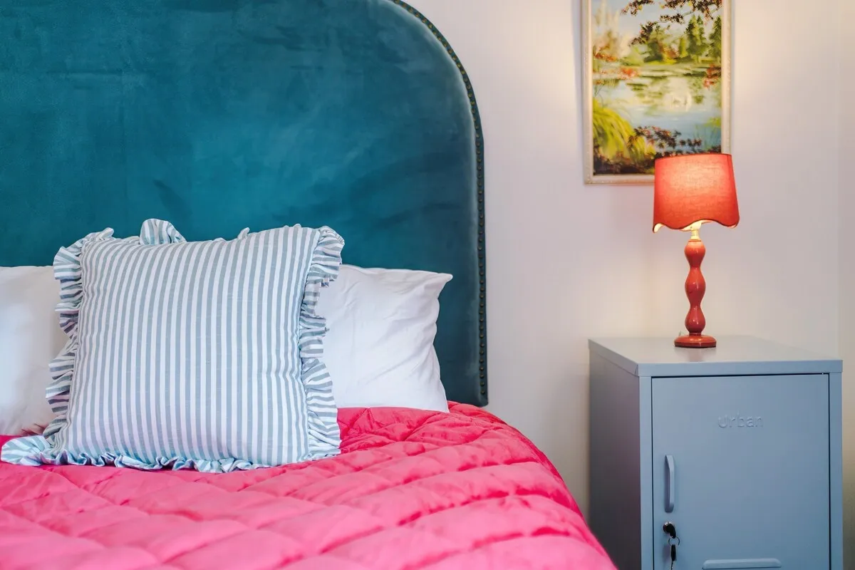 Bedside table and lamp beside the pink double