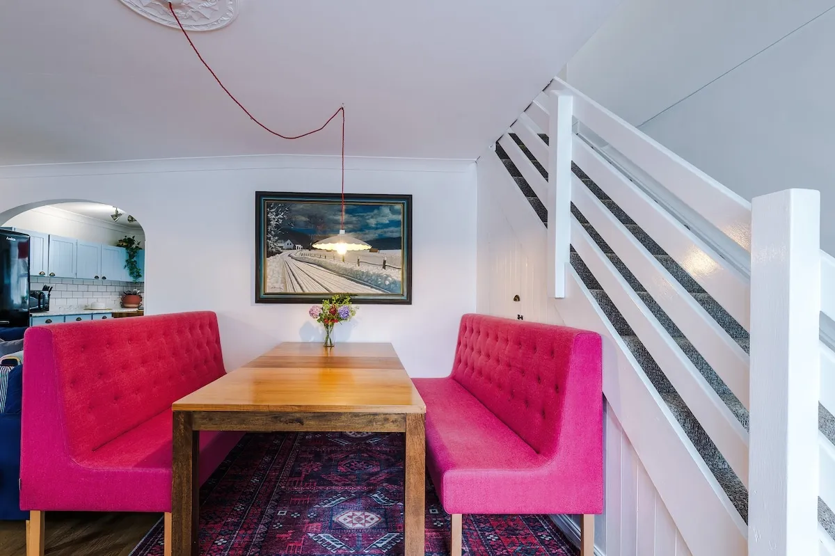 Dining table with pink banquette seats under the stairs