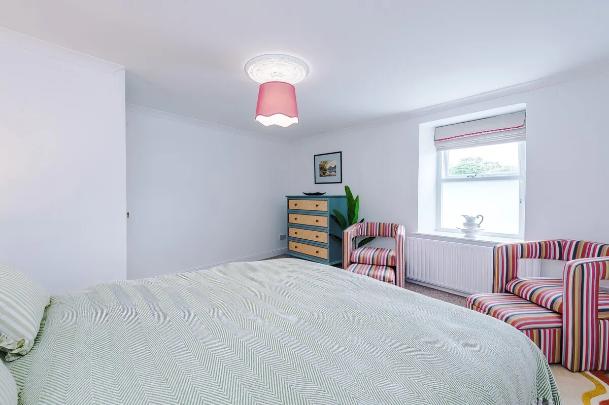 Double bedroom with striped armchairs and a green throw
