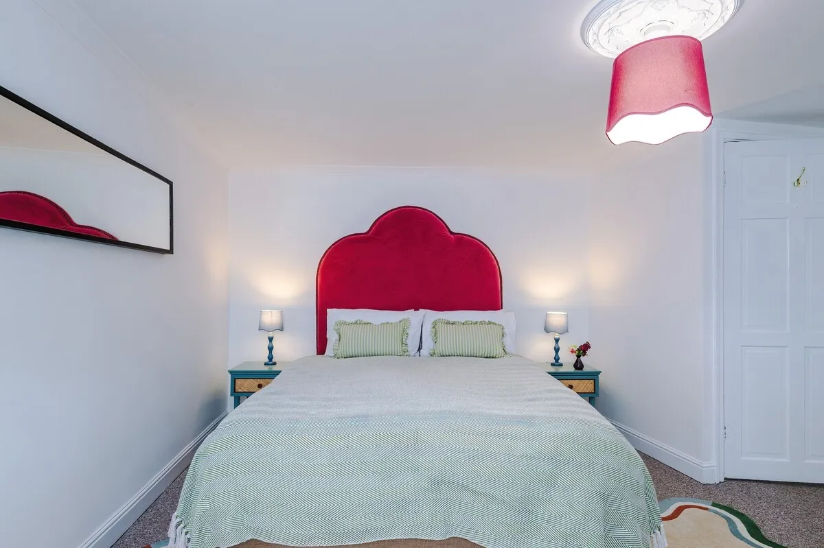 Double bed with a red velvet headboard and lamps either side