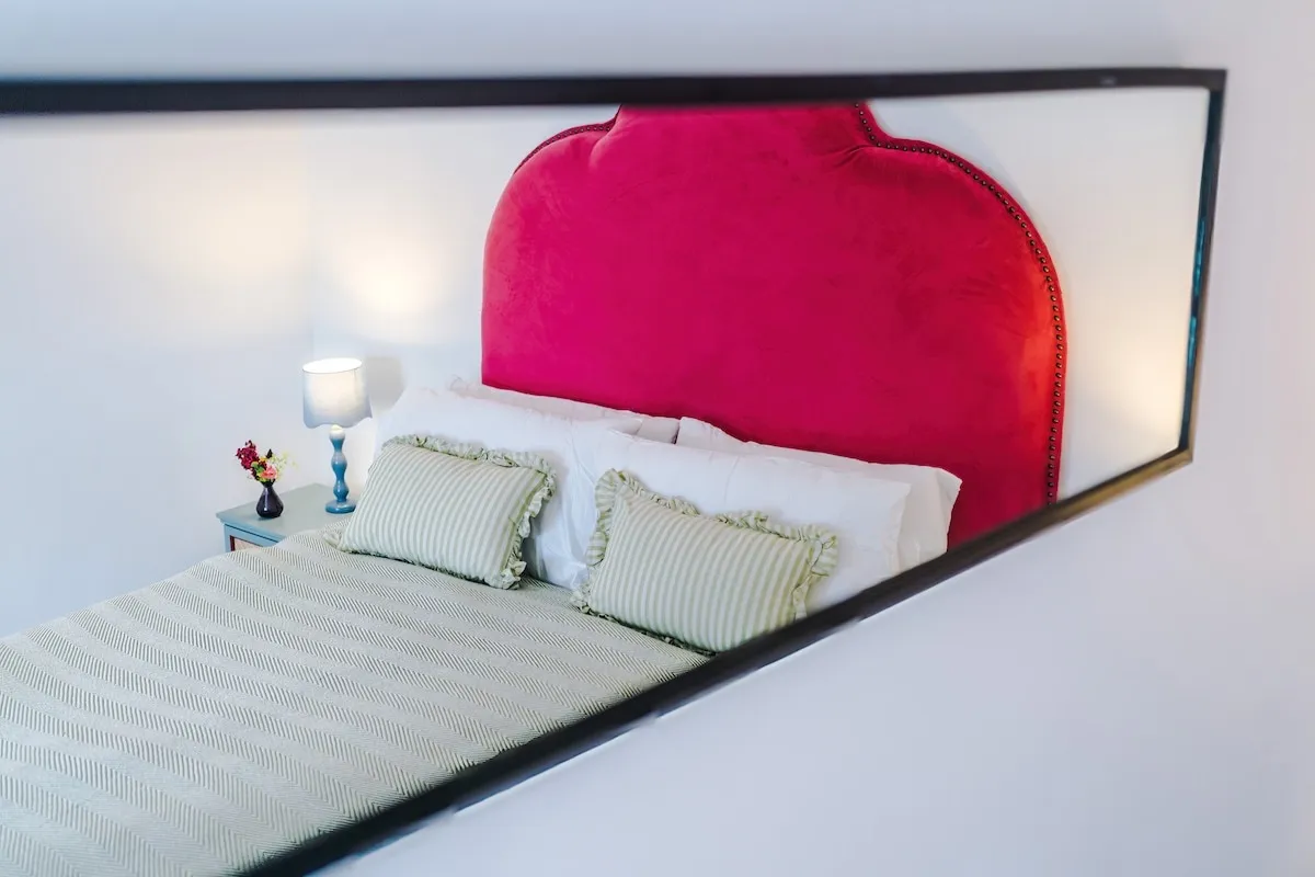 Red headboard reflected in a long mirror