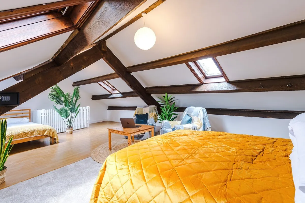 Attic bedroom with beams, skylights and a palm