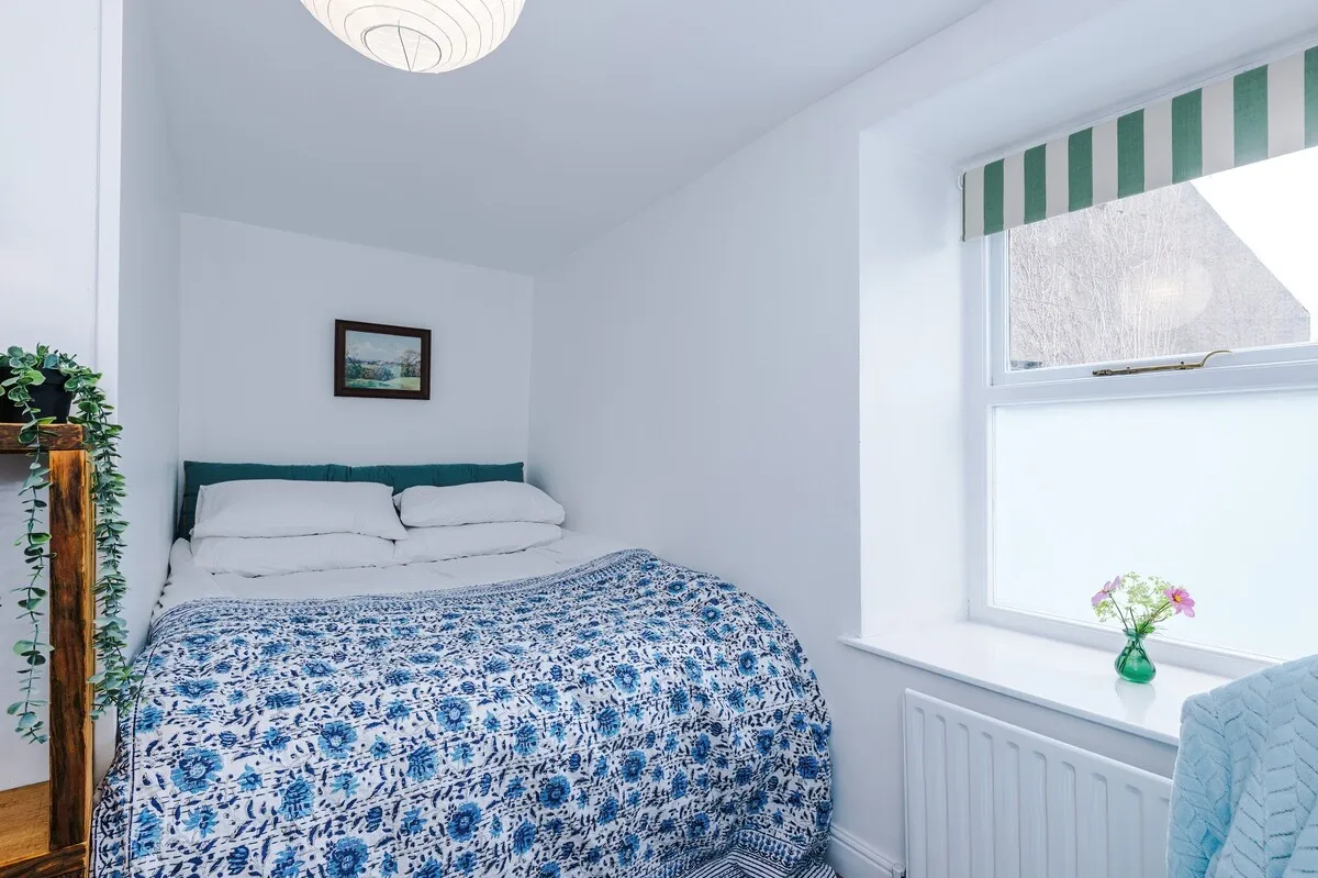 Double bedroom with a blue floral quilt by the window