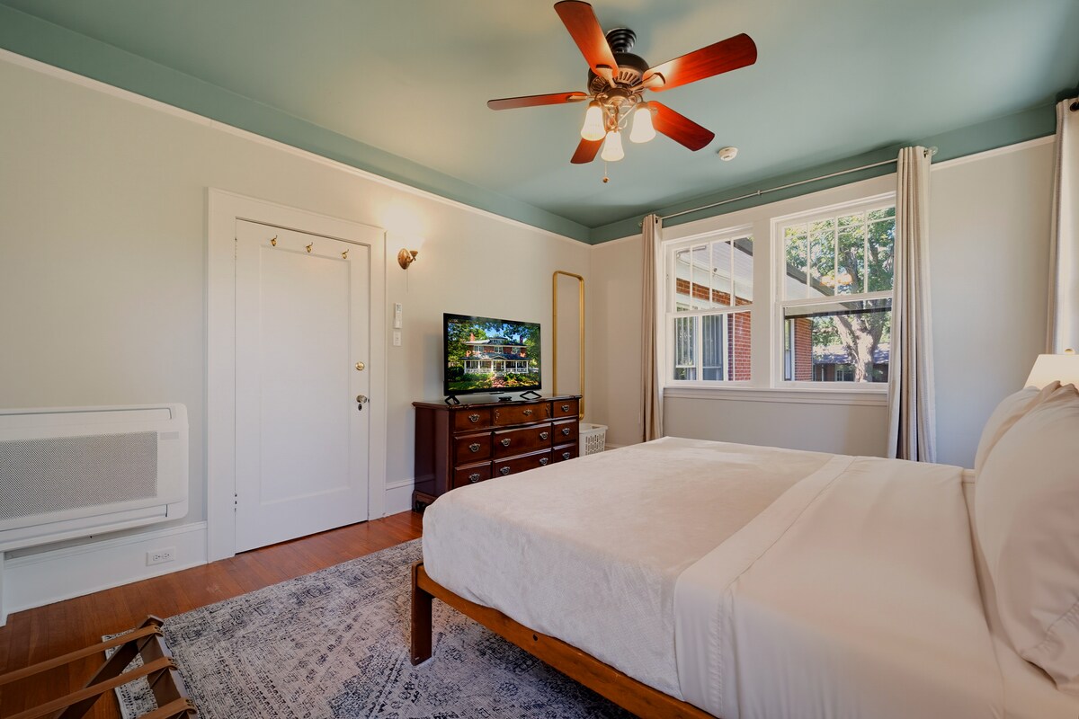 A hotel room with a bed, TV, and window