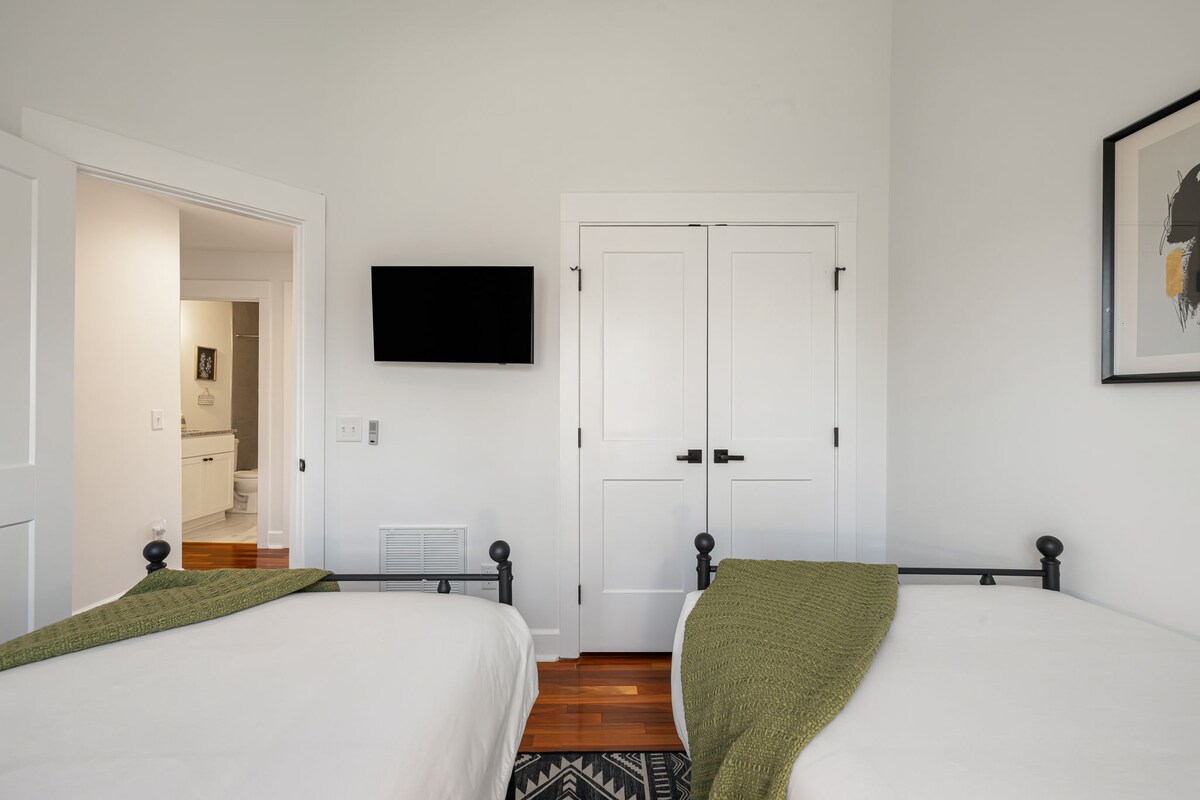 A hotel room with two beds, a TV, closet, and artwork