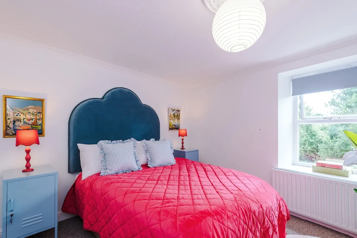 Double bedroom with a velvet headboard and pink quilt