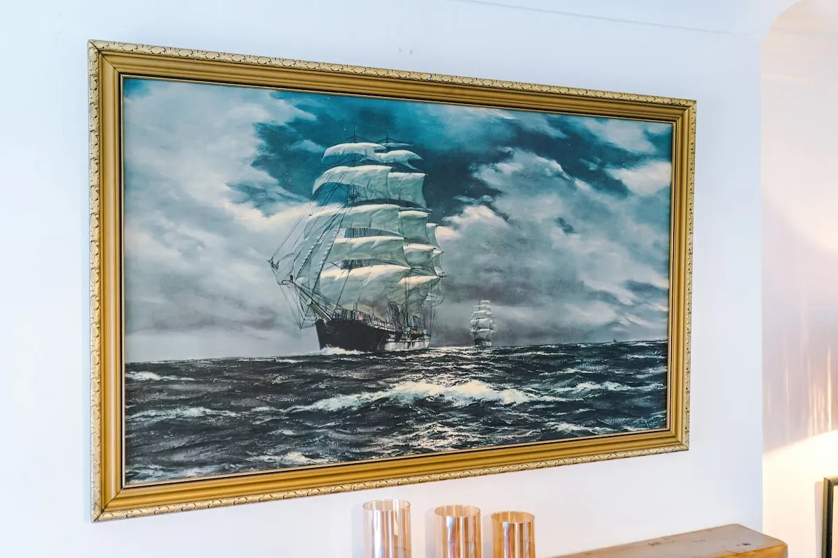 Oil painting of a tall ship at sea above the sofa